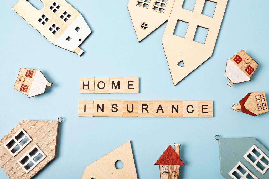 Home insurance message and wooden houses over blue background