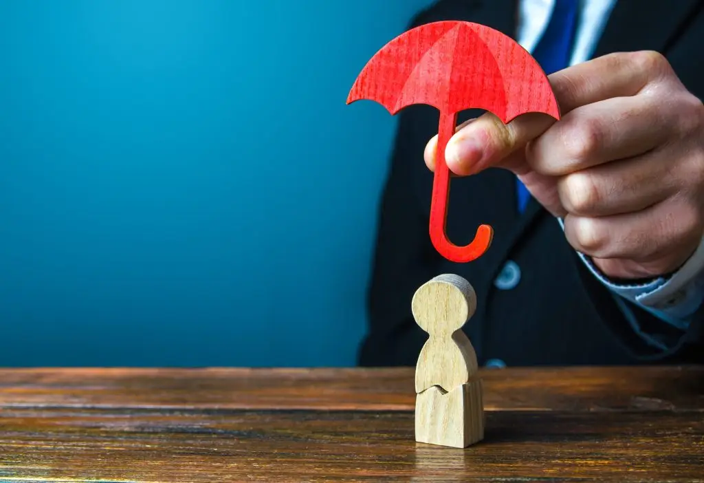 Insurance agent holds an umbrella over a men with a crack.