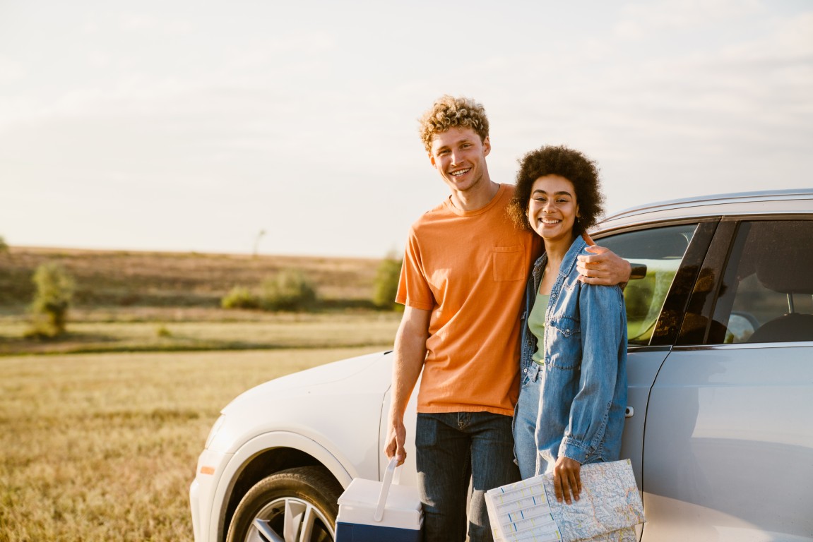 Young multiracial couple smiling and hugging during car trip